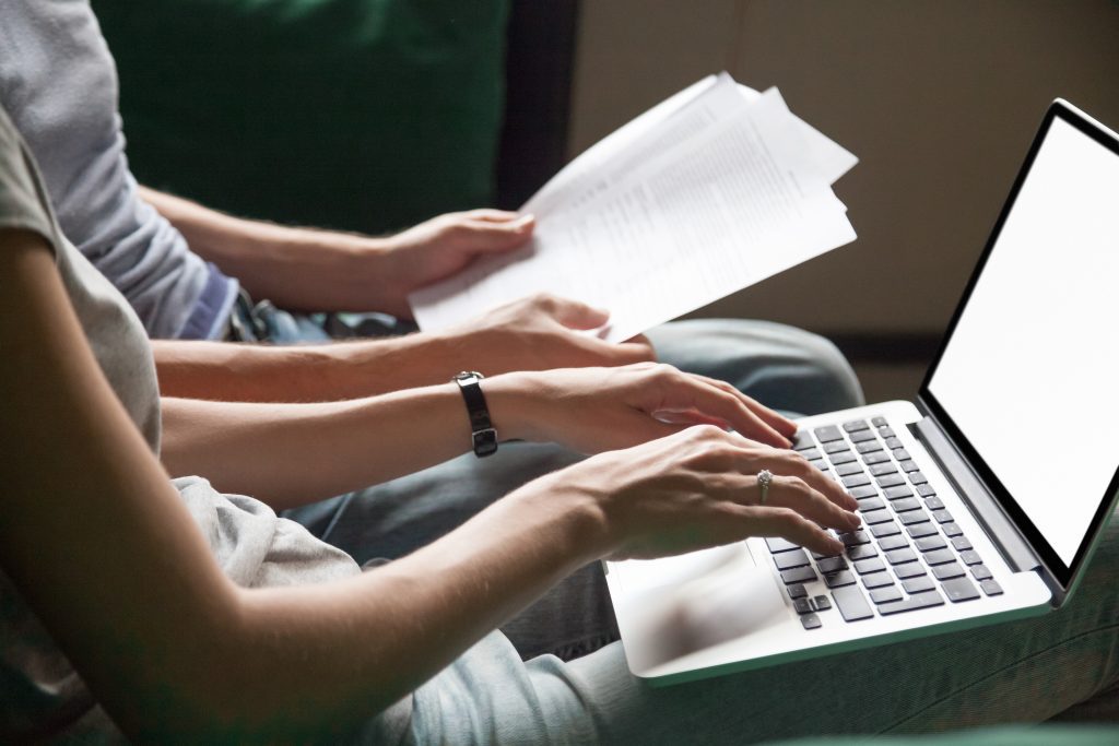 Close up of couple searching online information about legal document details with laptop, family studying important contract terms and conditions typing filling internet application form on website