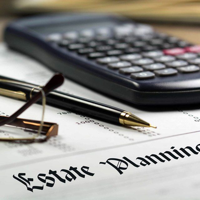 Glasses pen and calculator on top of written estate plan