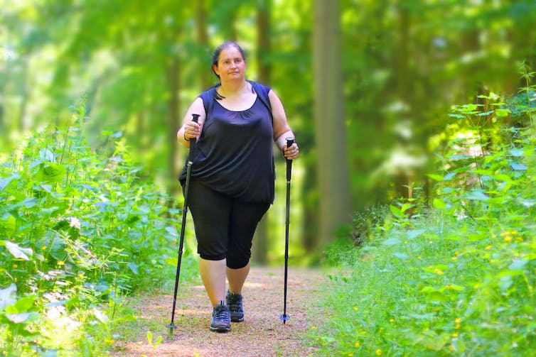 Woman walks on trail with poles
