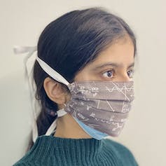 A young woman wearing a cloth face mask over a surgical mask