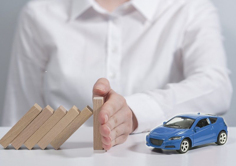 Authoritative person sitting in front of gray background. His face is showing. Insuring the vehicle safely. Car insurance protects any damage to the vehicle. The hand of the person wearing the white shirt prevents the boards from damaging the falling vehicle.