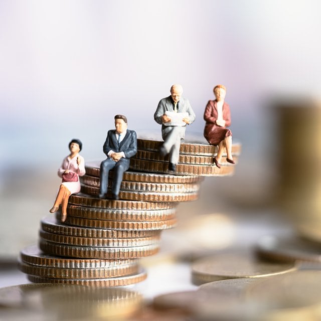 Figurines of people sitting on a stack of coins