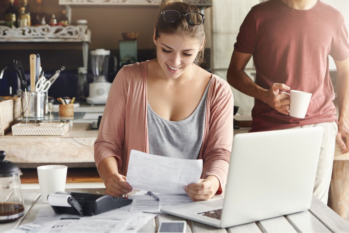 young woman wearing glasses her head smiling happily while reading document saying that bank approved their mortgage application