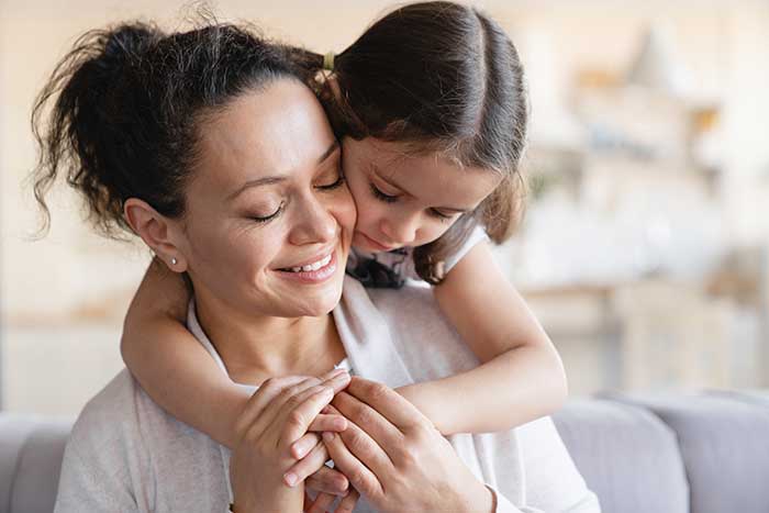 Mother sitting on a couch with her young daughter behind her - the daughter