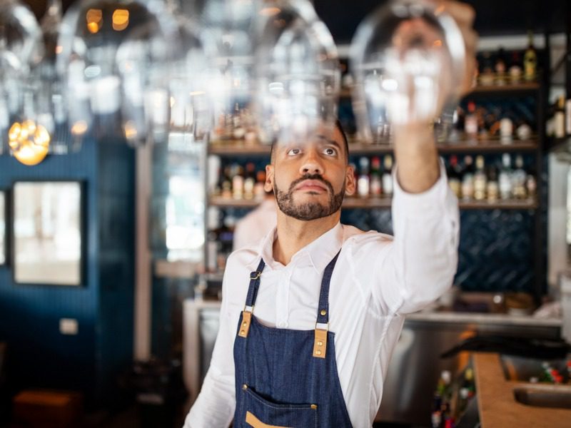 Bartender at restaurant reaching for a wine glass