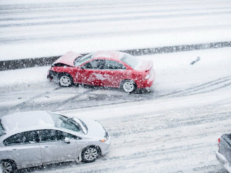 A red car has slid on the icy road and his into the freeway medium. A moderate traffic jam with two other white cars has occured