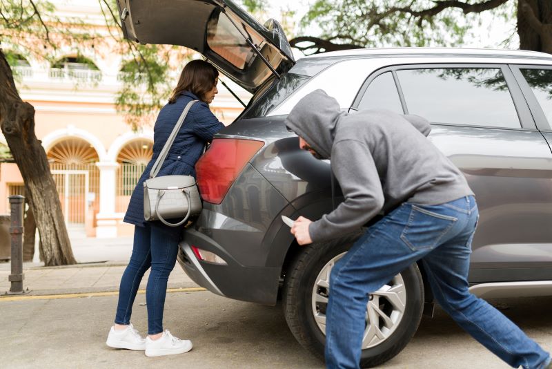 A man with a knife sneaks up on a woman loading her car