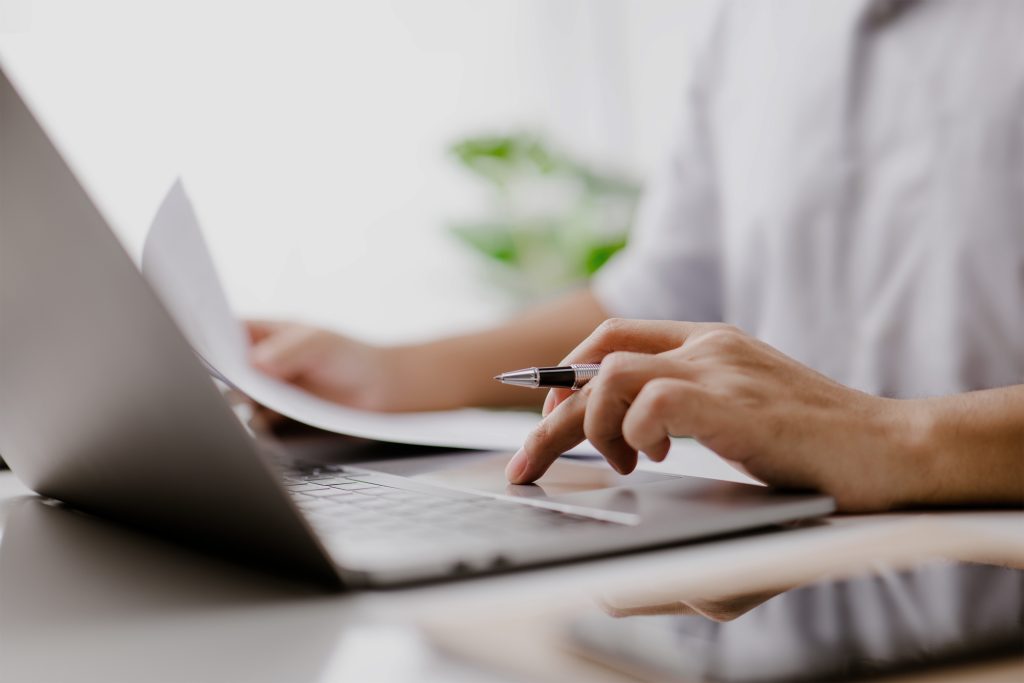 A photo shows using a laptop while filling out paperwork.