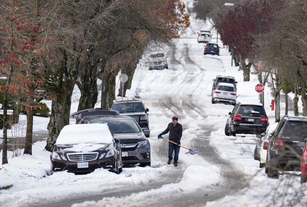 A man pauses while digging out snow from under a car stuck on a street in the aftermath of a snowstorm, in Vancouver, B.C., Wednesday, Nov. 30, 2022. Delta Mayor George Harvie describes the response to heavy snowfall in the region last week as a "recent failure of provincial highway winter maintenance." THE CANADIAN PRESS/Darryl Dyck