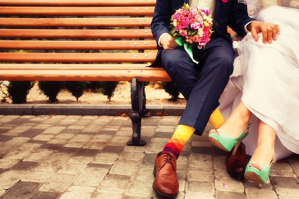 a bride and groom sitting on a wooden bench having just got married