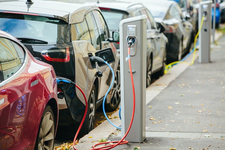 A line of electric cars plugged into curbside electrical charging stations