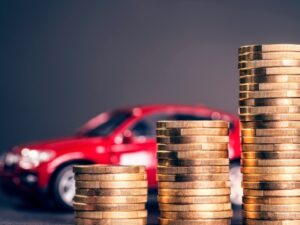 Stacks of coins increasing in size and a red car in the background