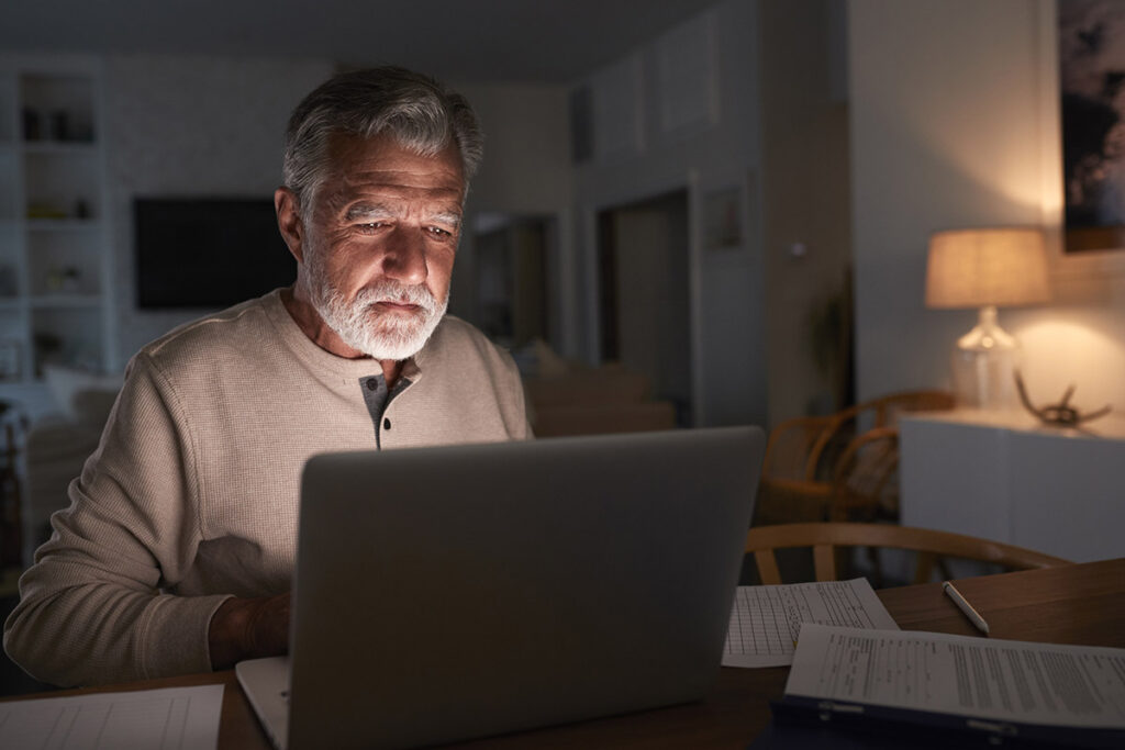 Older man using his laptop computer at night
