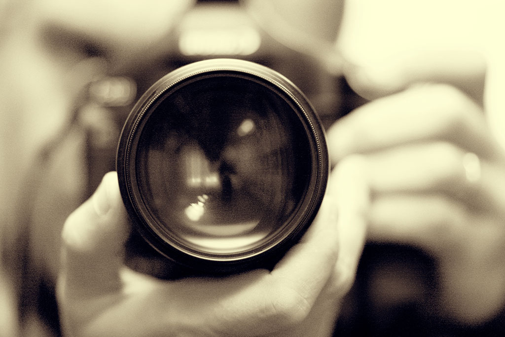 photographer with camera in hand looking through the camera lens