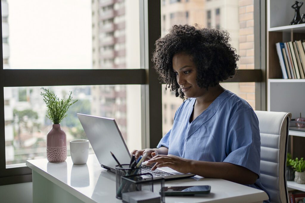 A nurse uses a laptop computer in an office