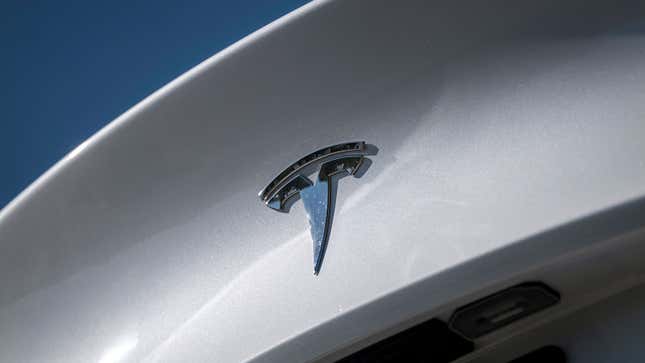 A photo of a Tesla badge on a car. 