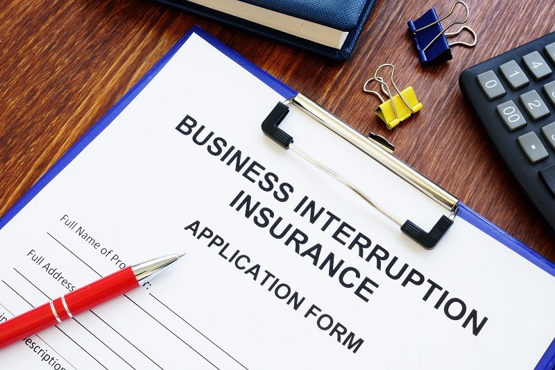 Business interruption insurance form and red pen for signing.