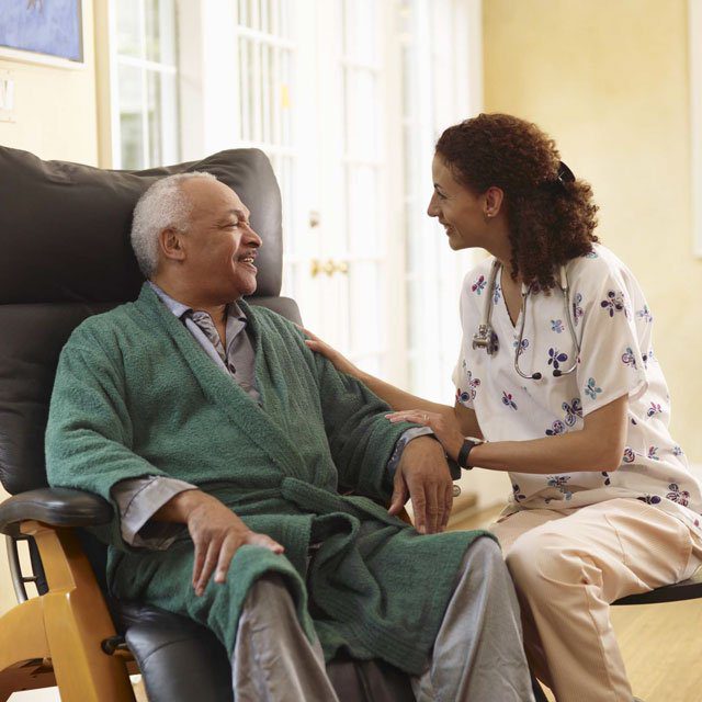 A woman looking at an older man in an armchair