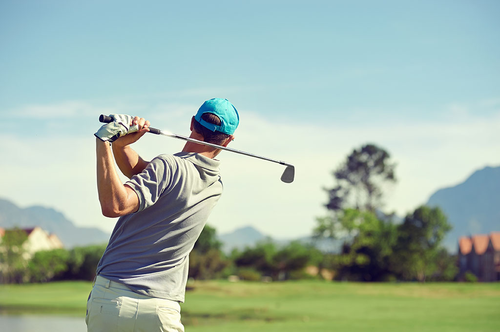 Golfer taking a swing with club on course on a summers day