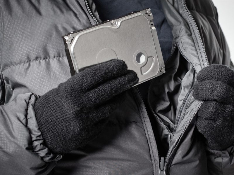 Cyber thief in black gloves hides a stolen hard drive