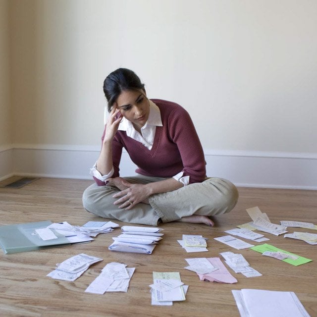 A woman sitting on the ground surrounded by bills