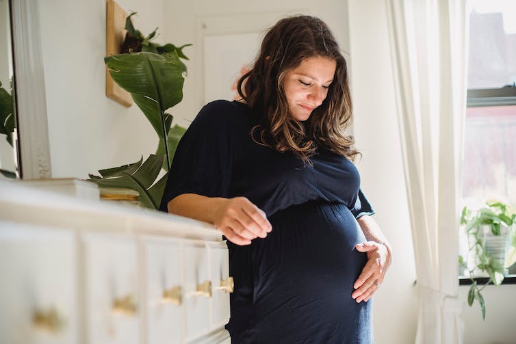 Pregnant woman holding belly.