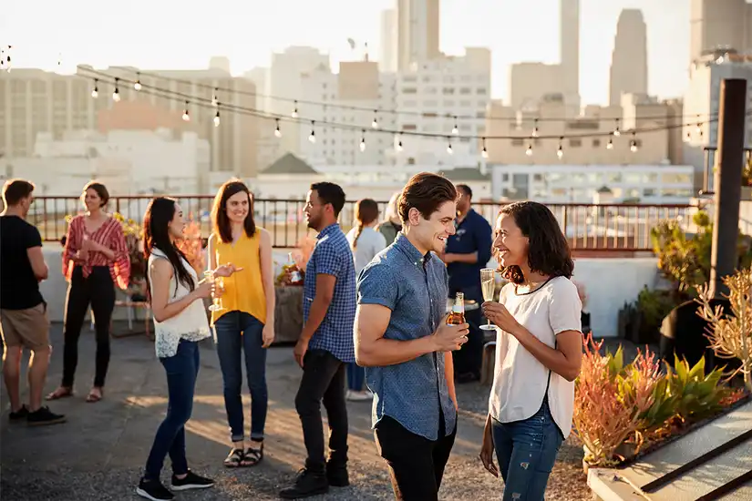 Friends Gathered On Rooftop Terrace For Party With City Skyline In Background