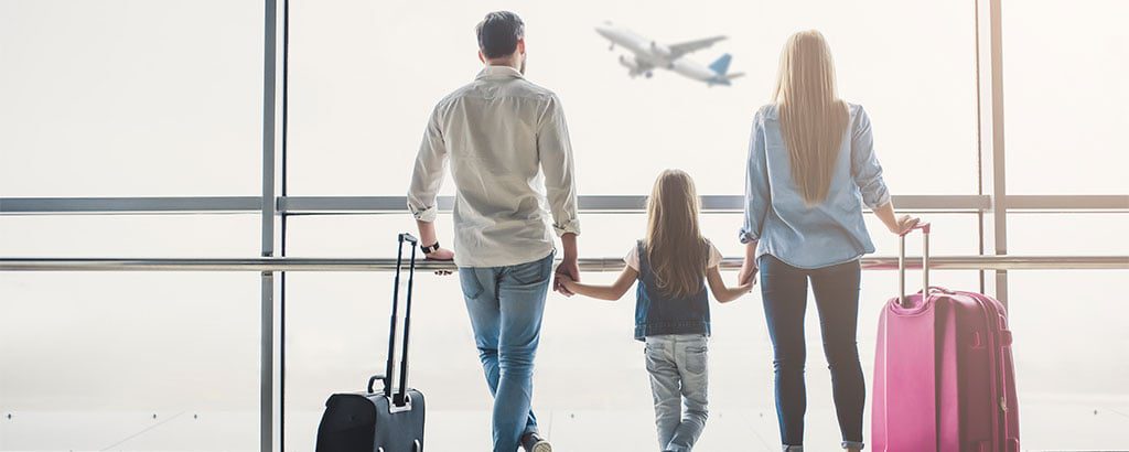 Family looking out window in airport watching a plane go by