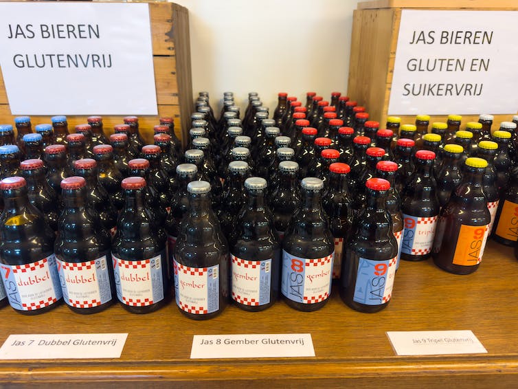Many rows of German beer bottles are lined up on a wooden table, with signs above them.