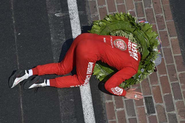 Marcus Ericsson of Chip Ganassi Racing dons his victory wreath and ring while kissing the yard of bricks on the front stretch of the Indianapolis Motor Speedway after winning the 2022 edition of the race.