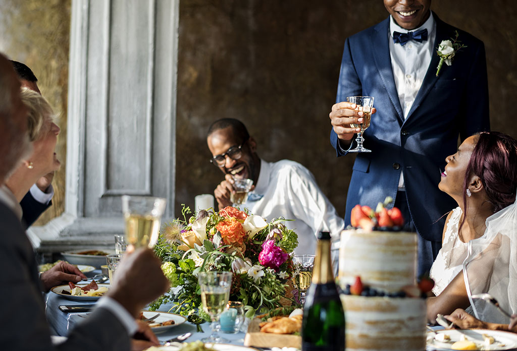 A group of people at a wedding laughing at a speech. 