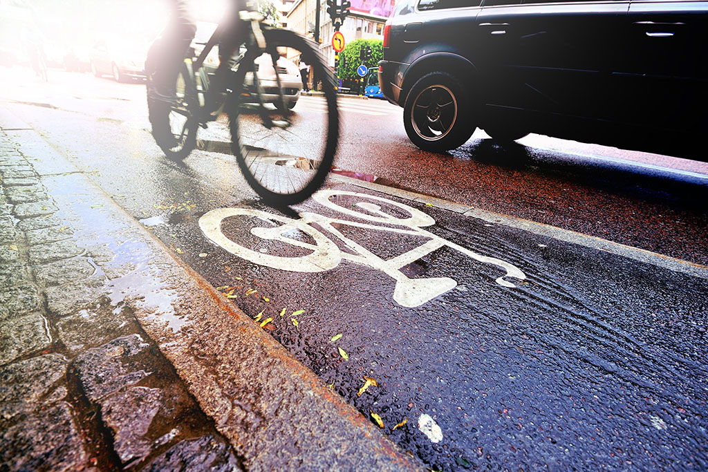 Cycle lane with someone cycling on it next to a car 