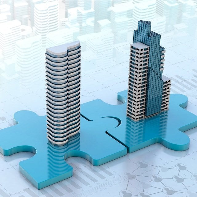 Two buildings on puzzle pieces representing mergers & acquisitions or M&A