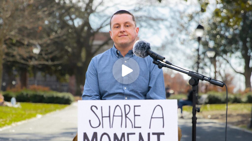 Mike Sizemore seated at table with poster that says "Share a Moment that Changed Your Life"