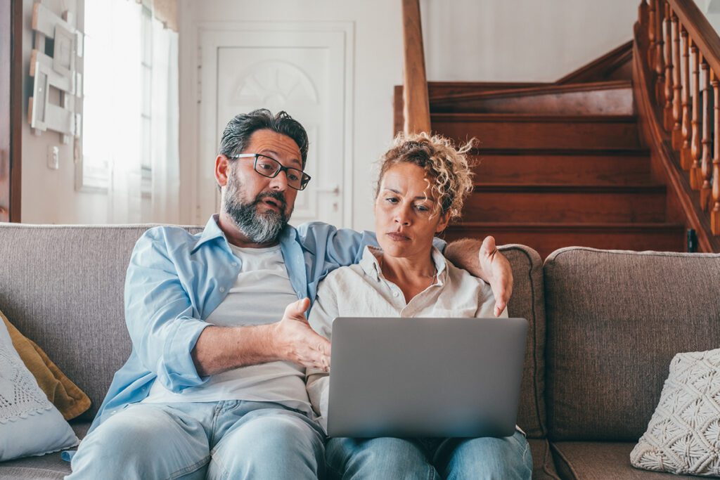 A couple looks up information about health insurance on their laptop.