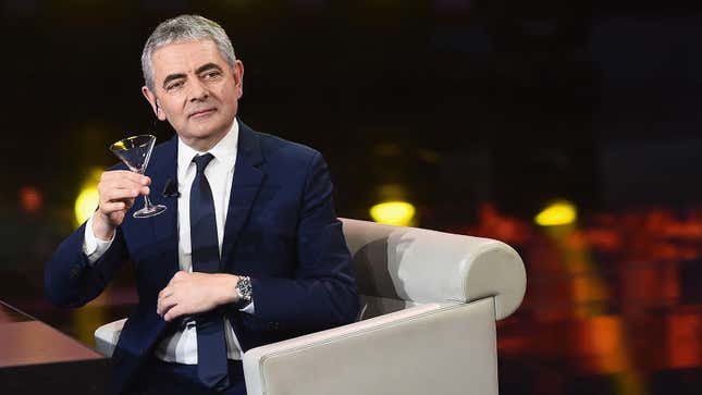 A photo of Rowan Atkinson holding a Martini glass. 