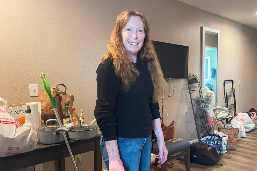 A photo of Annie Malloy standing for a photo as she cleans the motel room she had been living in.