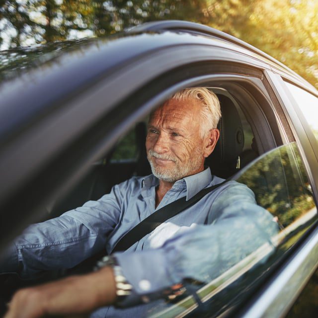 A senior man driving a car