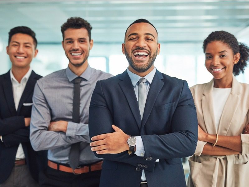 Four young businesspeople standing with arms crossed and smiling at the camera