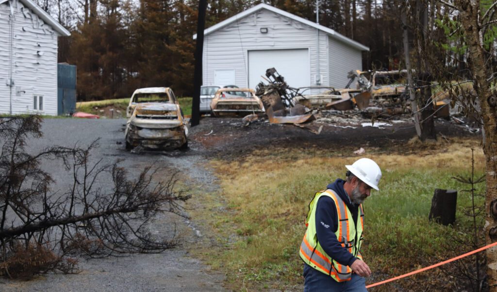 A worker crosses past damage from a wildfire in Hammond's Plains, N.S., during a media tour, Tuesday, June 6, 2023. THE CANADIAN PRESS/POOL, Tim Krochak