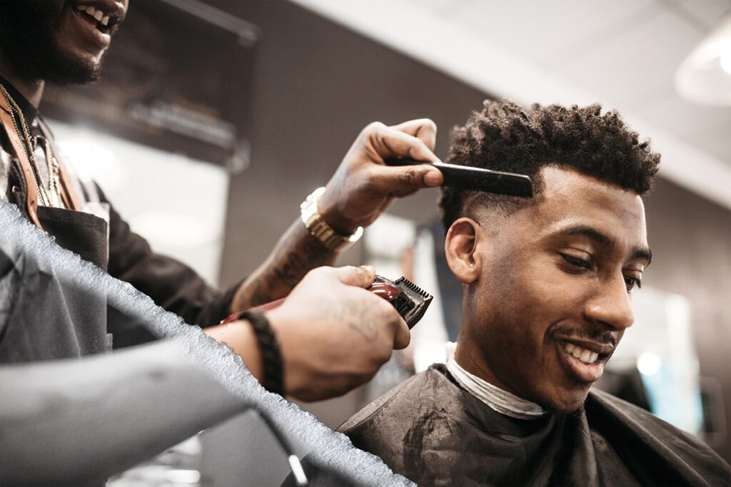 An African American man gets his hair cut by a skilled stylist at the barbershop.