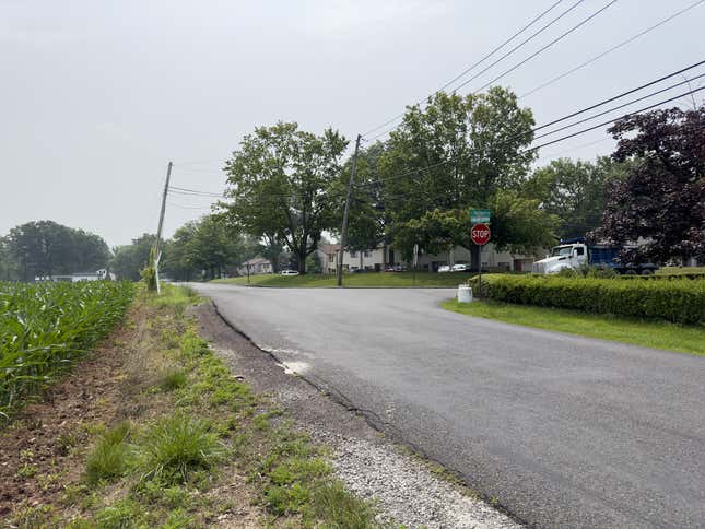 Photo of the same intersection as earlier, but taken from another road meeting it that has a normal "Stop" sign.