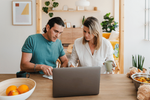 Couple checking bills to pay or domestic finances while going trough documents using laptop and sitting at the table at home.