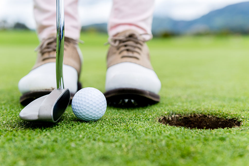 golfer about to putt the ball into the hole