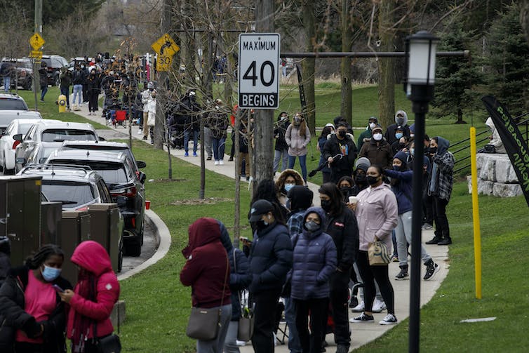 A long line of people queuing on a sidewalk