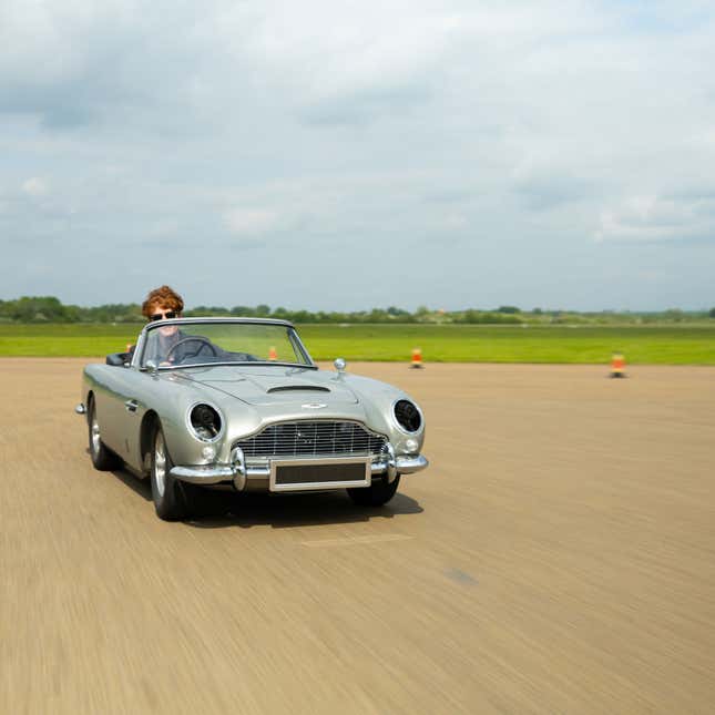 A photo of an Aston Martin DB5 driving on a track. 