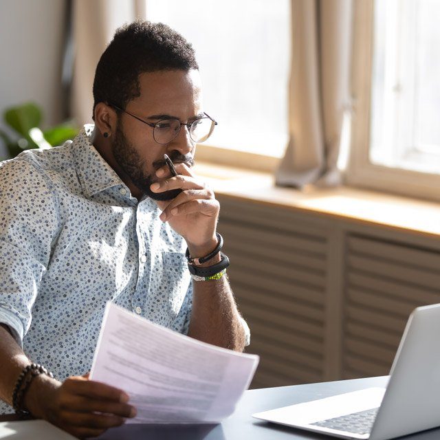 A man holding documents looking at a computer