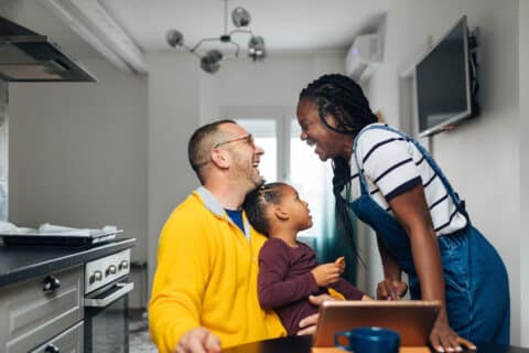 Portrait of beautiful mixed race family watching cartoons together at home on digital tablet