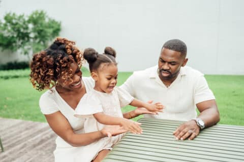 Mom, Dad, and Daughter spend quality time at the park holding hands, walking, laughing, and dancing