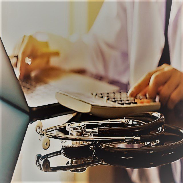 A physician using a computer, with a stethoscope in the foreground.